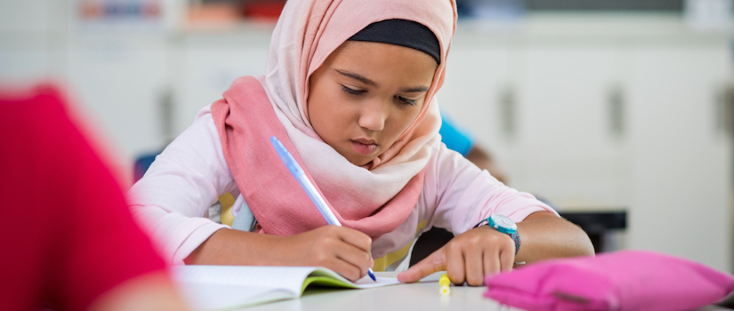 “student-handwriting-at-desk-in-classroom“